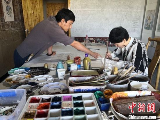 圖為2020年8月下旬，敦煌“80后”畫家張杰龍(左)在為云南麗江“學生”莫北講解敦煌壁畫的繪畫技巧。　馮志軍 攝