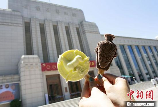2021年7月30日，游客手拿“銅奔馬”“彩陶瓶”造型的雪糕，在甘肅省博物館前拍照打卡?！「哒?攝