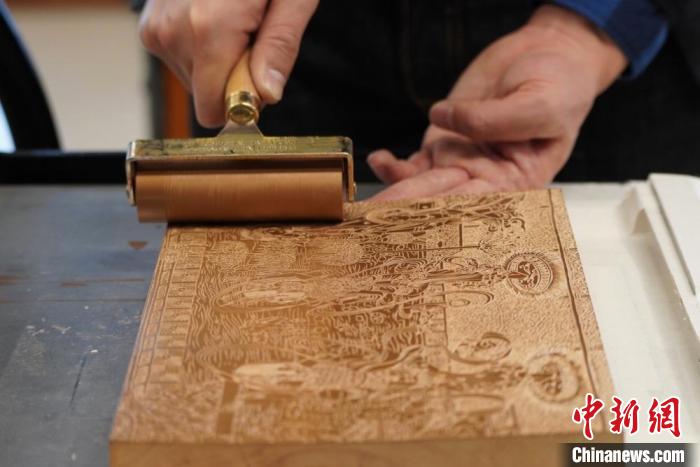 圖為徐晉林工作室工作人員正在給雕好壁畫的版面滾油墨?！【琶赖┰?　攝