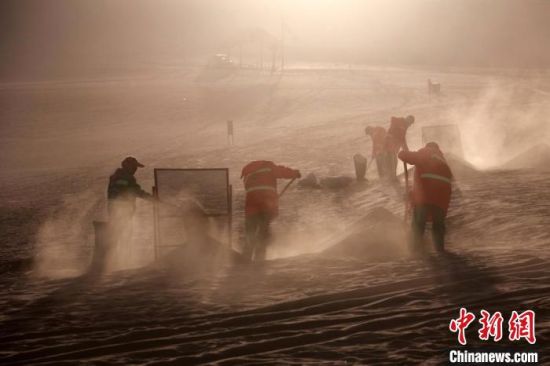 圖為敦煌市鳴沙山月牙泉景區(qū)“駱駝保姆”清理駱駝糞便?！垥粤?攝