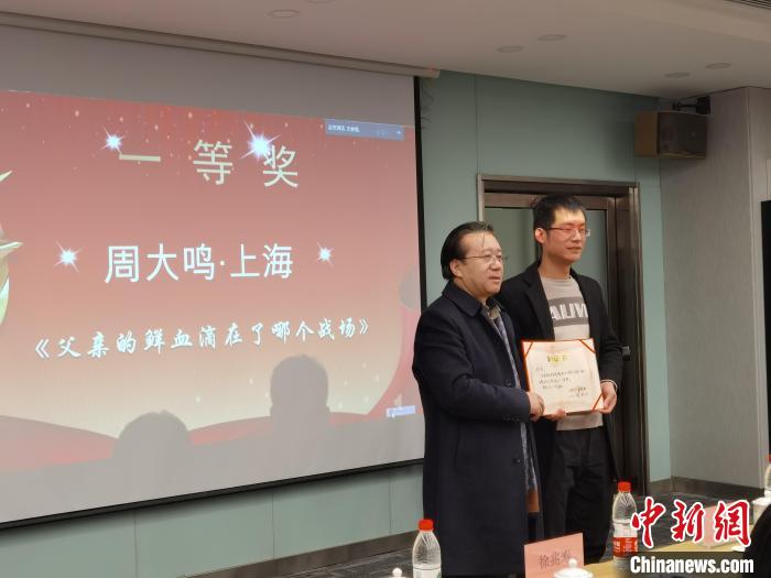 圖為作家、西北師范大學(xué)新聞與傳媒學(xué)院院長徐兆壽頒發(fā)一等獎證書，代領(lǐng)獎?wù)呱吓_領(lǐng)獎?！钅?攝