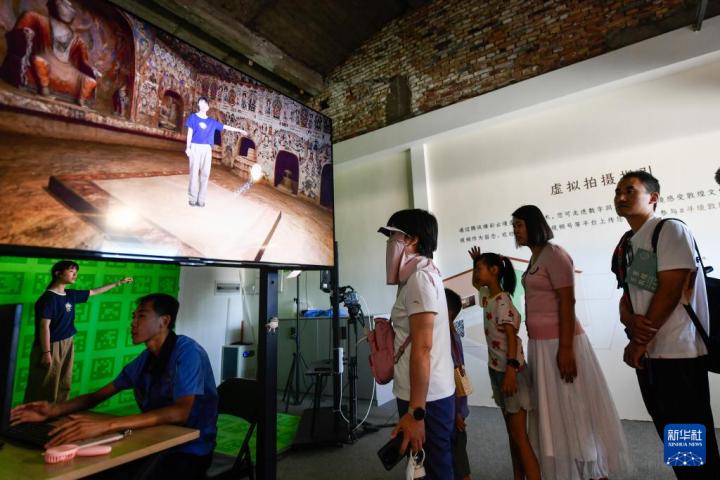 7月22日，游客體驗(yàn)“尋境敦煌——數(shù)字敦煌沉浸展”后，在虛擬演播廳拍攝一段真人與洞窟虛擬場(chǎng)景交互的視頻。新華社記者 郎兵兵 攝</p>
<p>