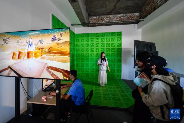 7月22日，游客體驗(yàn)“尋境敦煌——數(shù)字敦煌沉浸展”后，在虛擬演播廳拍攝一段真人與洞窟虛擬場(chǎng)景交互的視頻。新華社記者 郎兵兵 攝</p>
<p>